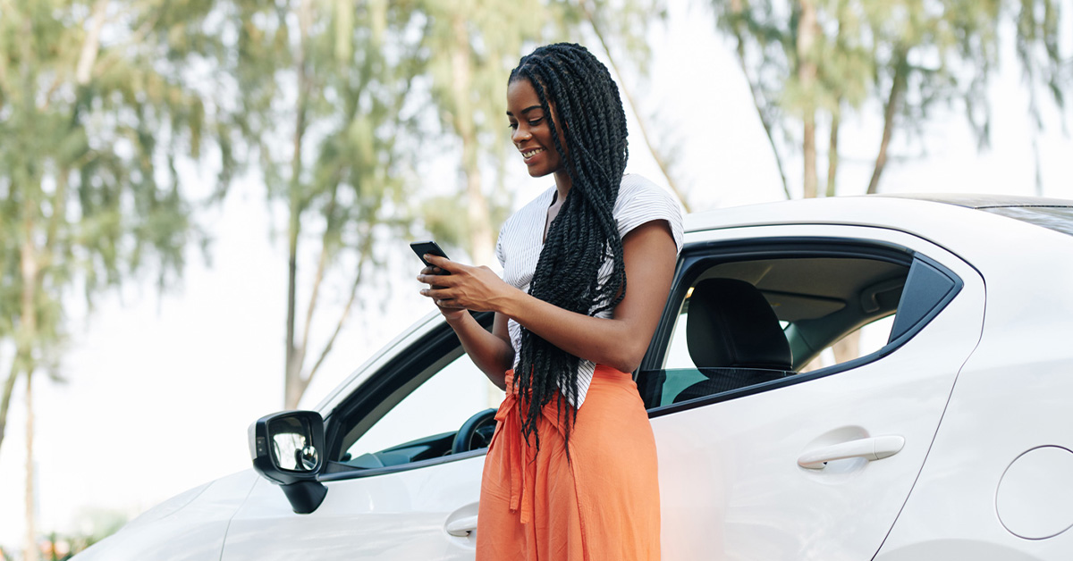woman interacting with smartphone by car